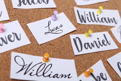 Photo of Paper pieces with baby names on cork board, closeup