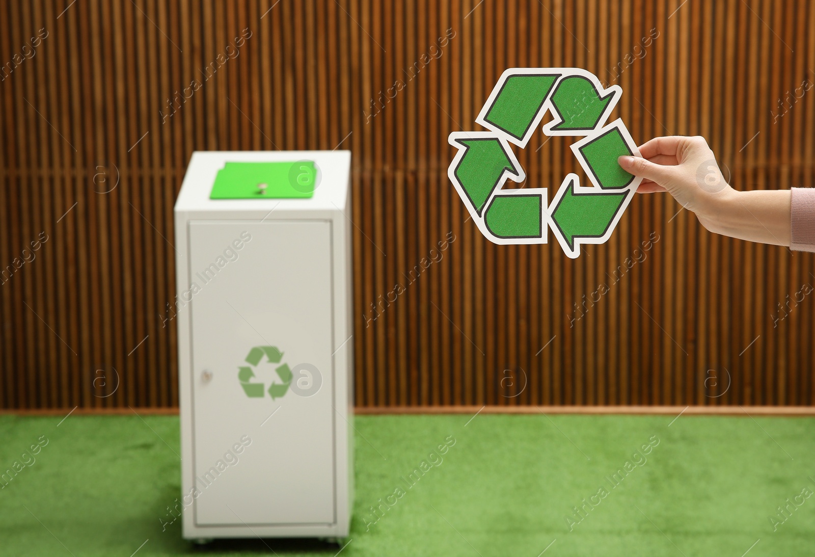 Photo of Closeup view of woman with recycling symbol and blurred trash bin on background. Space for text