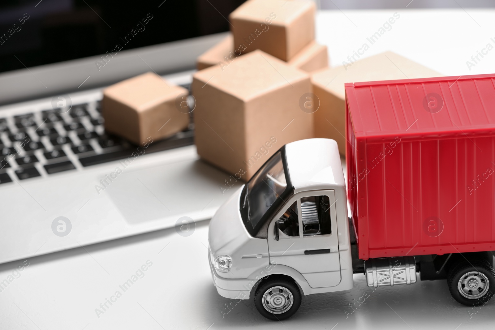 Photo of Toy truck near laptop on table. Logistics and wholesale concept