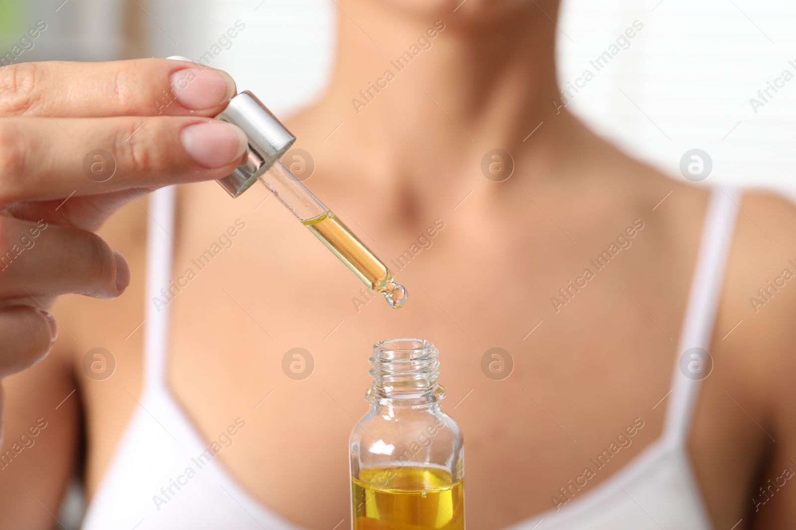 Photo of Woman with bottle of cosmetic serum on blurred background, closeup