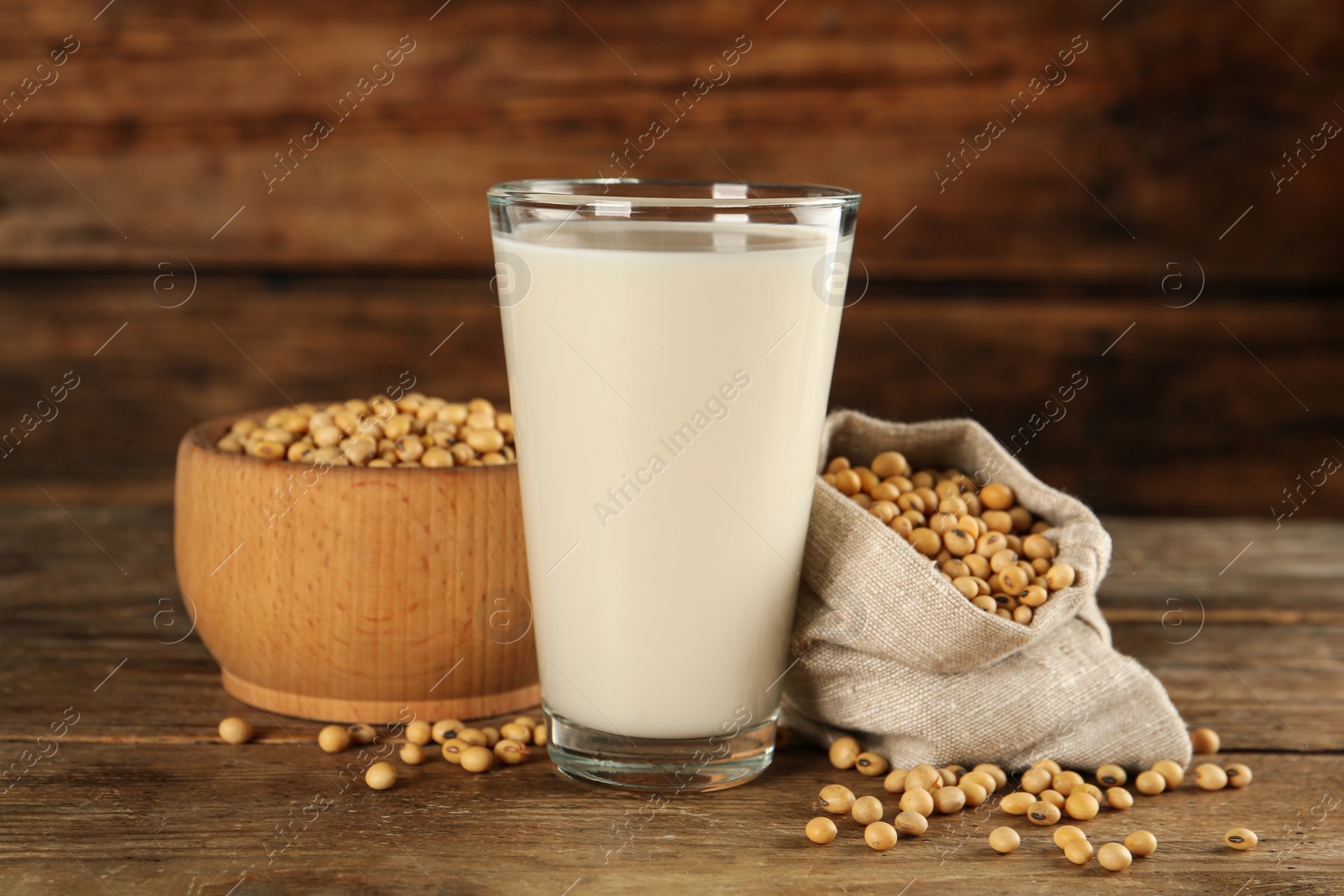 Photo of Glass with fresh soy milk and grains on wooden table