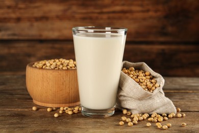 Glass with fresh soy milk and grains on wooden table