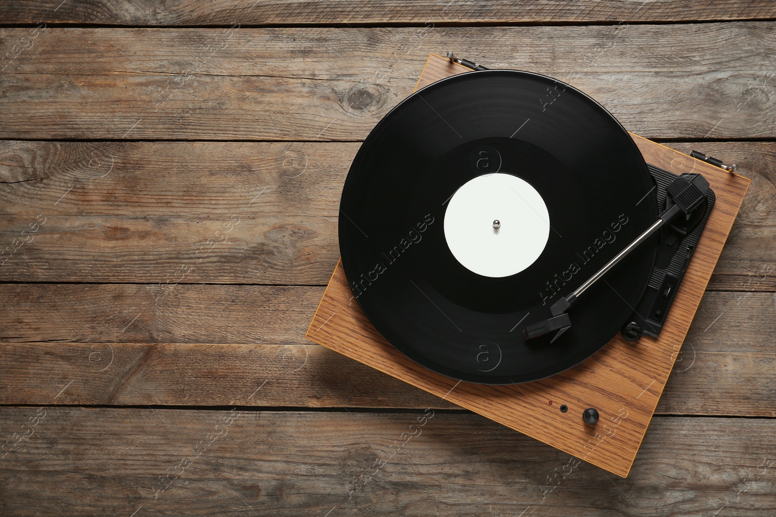 Photo of Turntable with vinyl record on wooden background, top view. Space for text