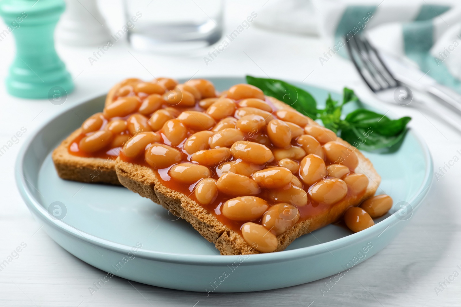 Photo of Toasts with delicious canned beans on white wooden table, closeup