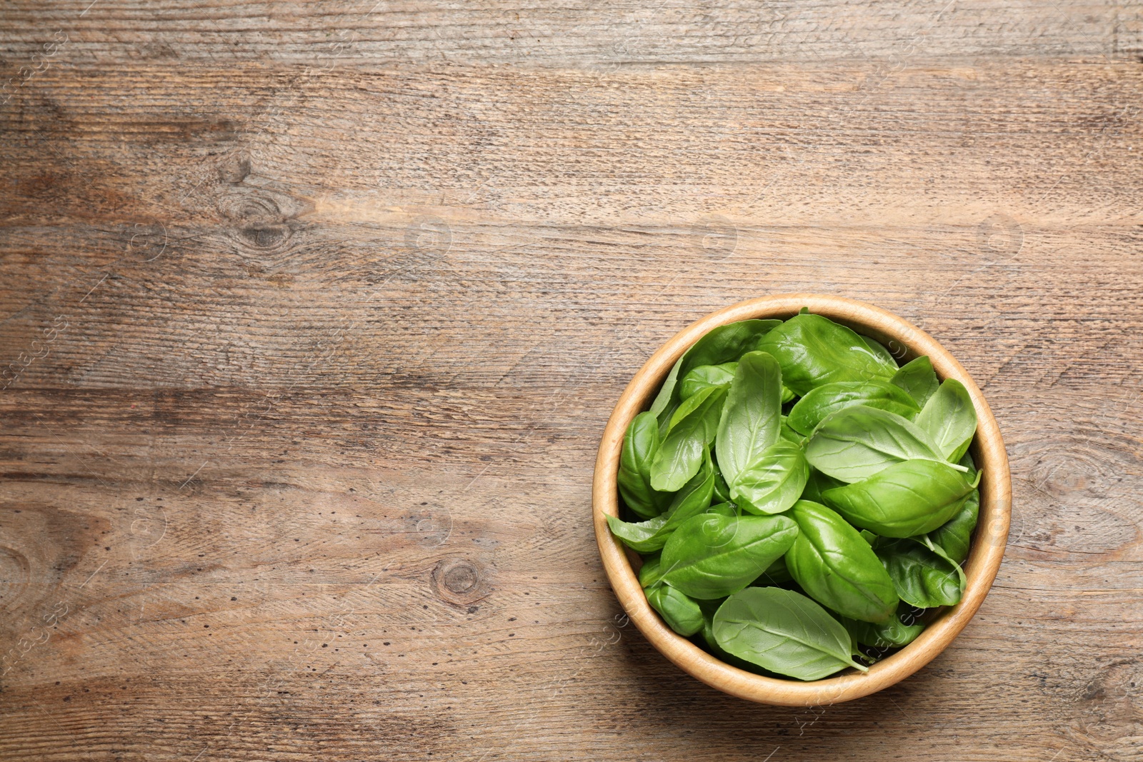 Photo of Fresh basil on wooden table, top view. Space for text