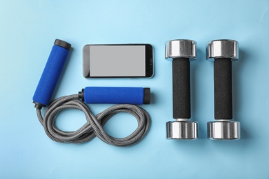 Photo of Flat lay composition with jump rope and smartphone on color background