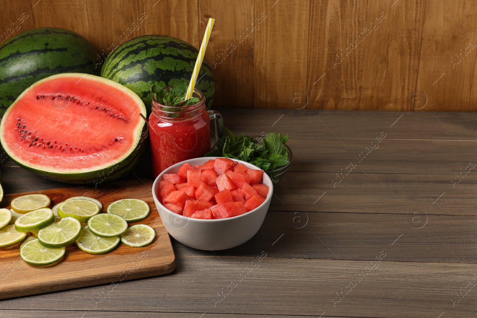 Photo of Tasty watermelon drink with lime and fresh ingredients on wooden table, space for text