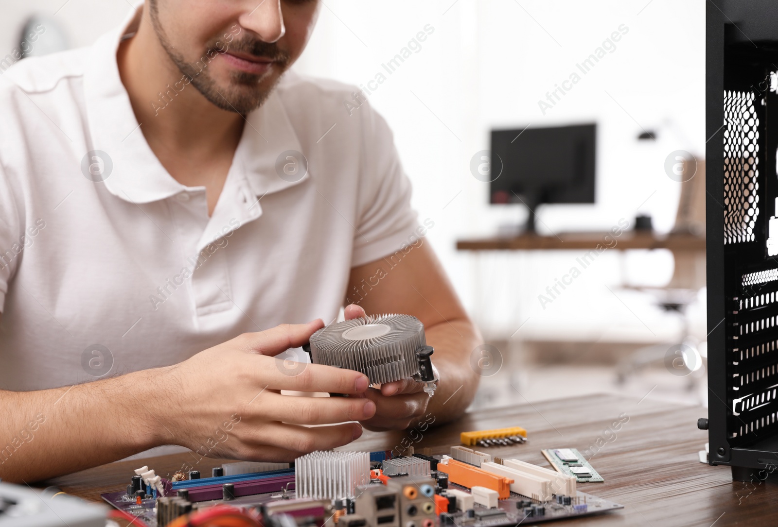 Photo of Male technician repairing computer at table indoors, closeup