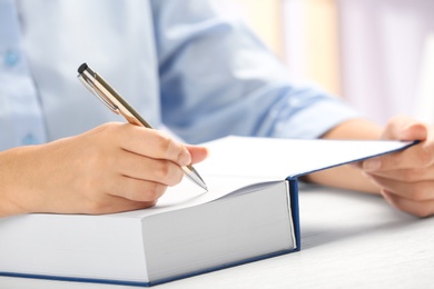 Writer signing autograph in book at table, closeup