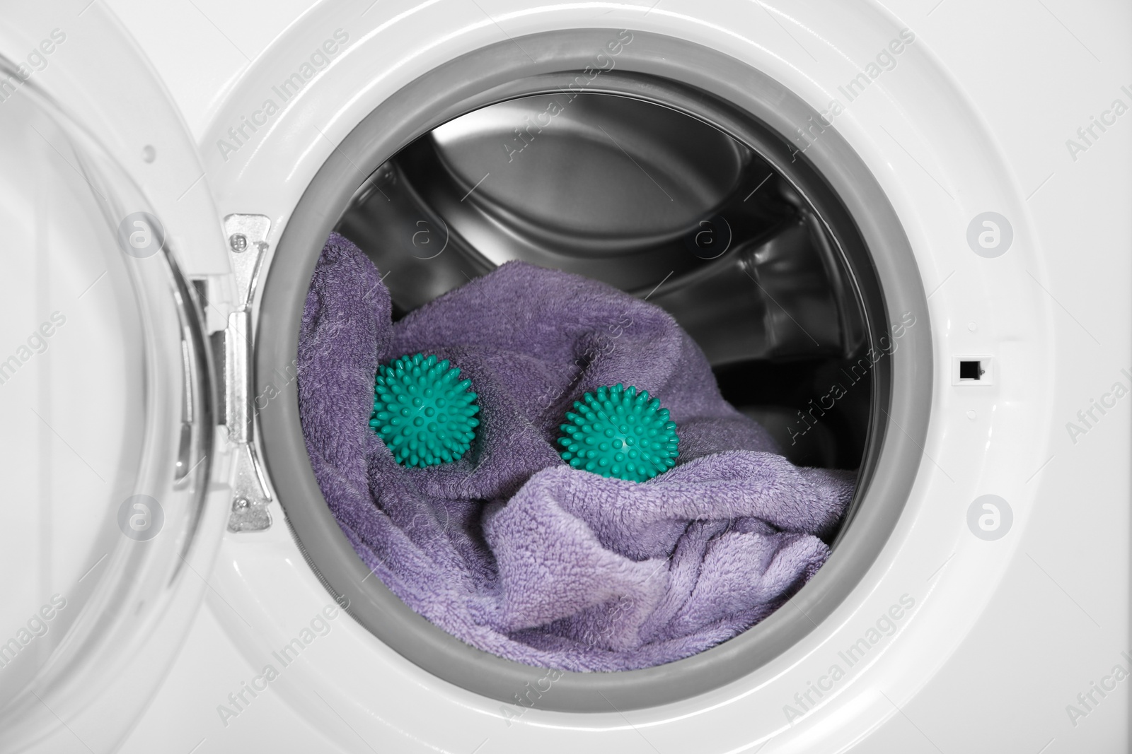 Photo of Green dryer balls and towel in washing machine drum