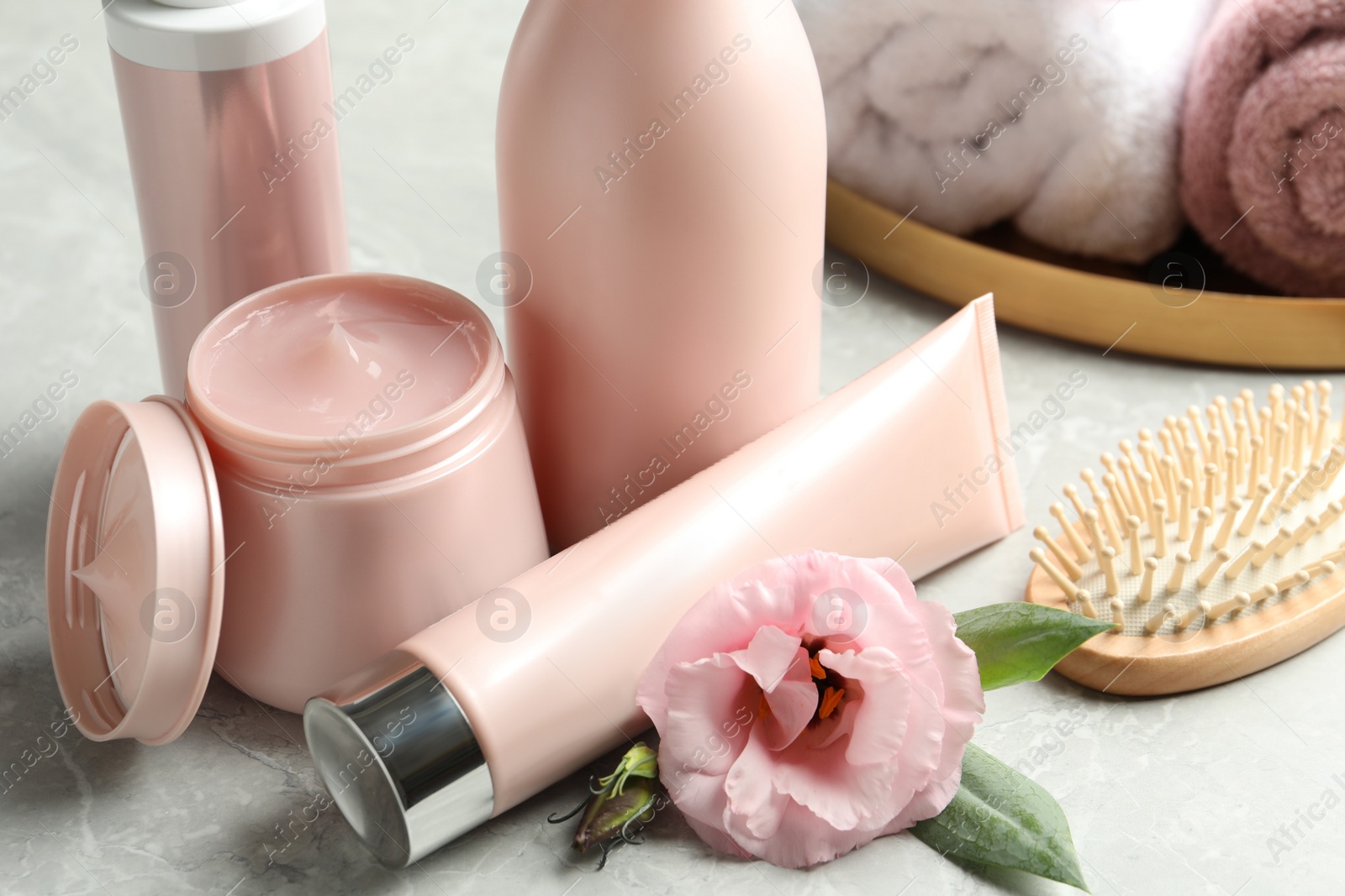 Photo of Set of hair cosmetic products, brush and flower on  grey table, closeup