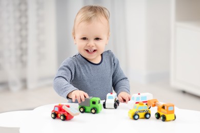 Photo of Children toys. Cute little boy playing with toy cars at white table in room