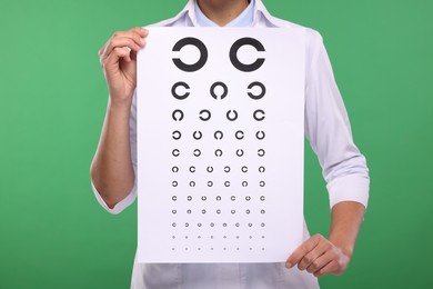 Photo of Ophthalmologist with vision test chart on green background, closeup