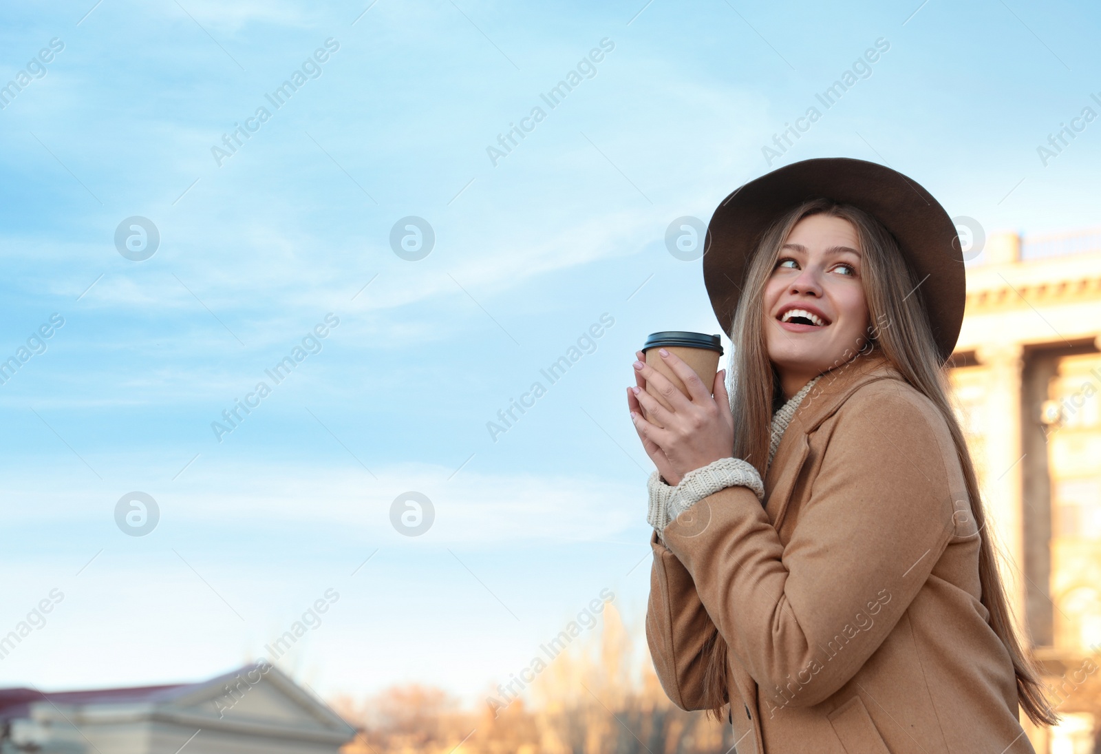 Photo of Young woman with cup of coffee on city street in morning