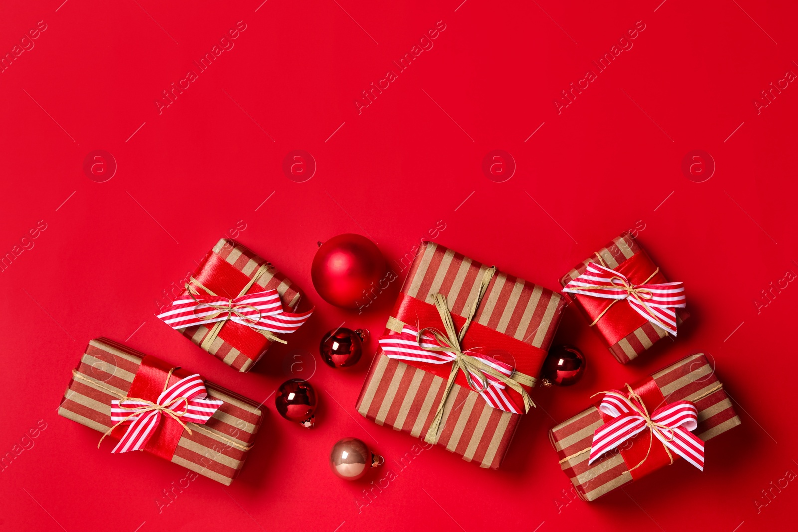 Photo of Gift boxes with Christmas balls on bright red background, flat lay. Space for text