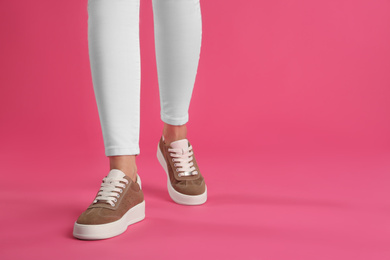 Photo of Woman wearing shoes on pink background, closeup. Space for text