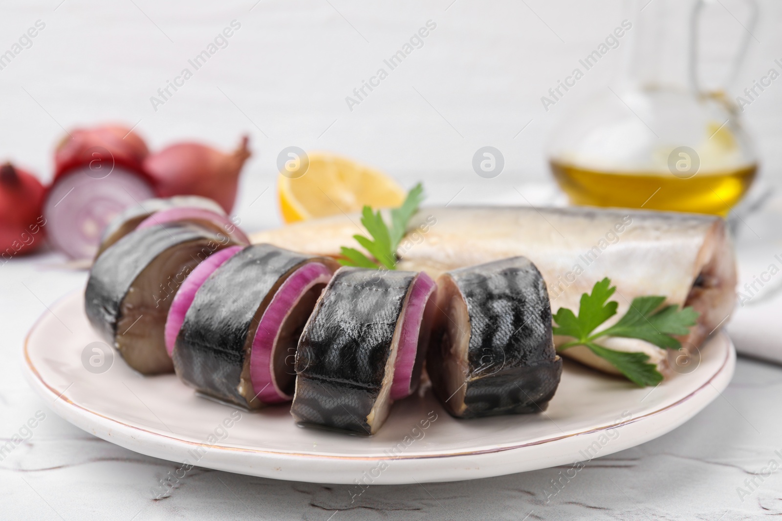 Photo of Tasty salted mackerel, parsley and onion on white textured table, closeup