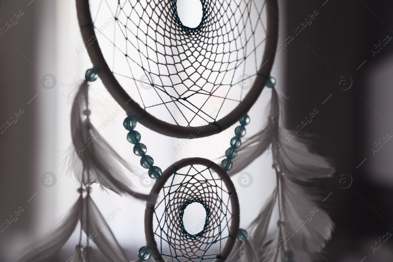 Photo of Beautiful dream catcher hanging against blurred background, closeup