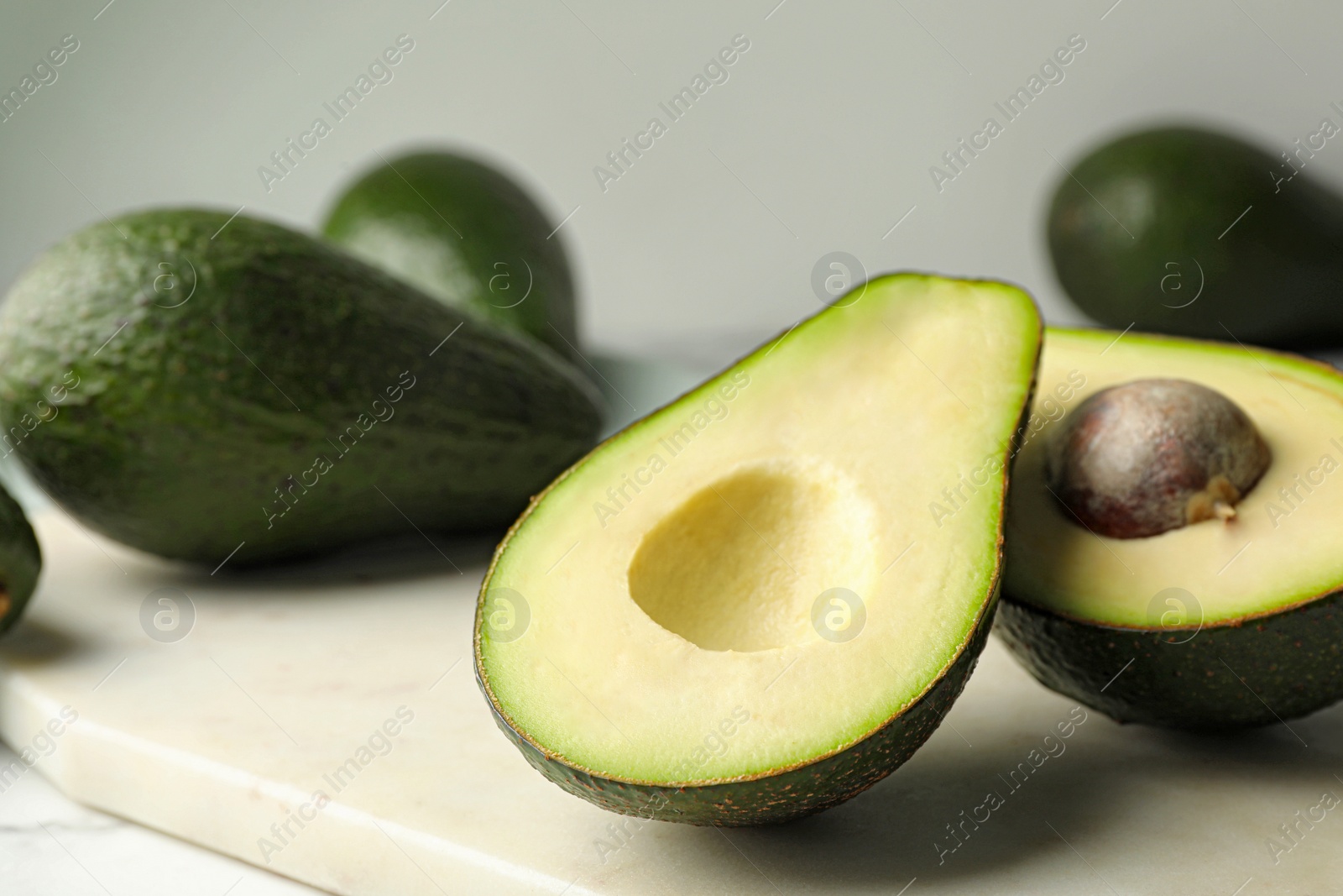 Photo of Delicious ripe avocados on table against light background