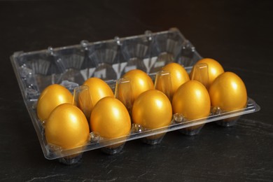 Shiny golden eggs in plastic box on black table