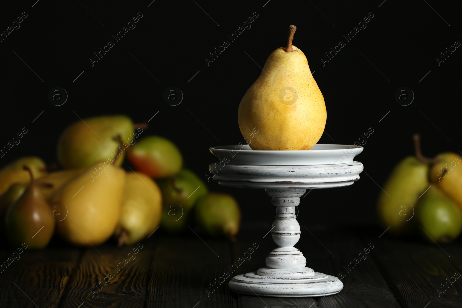 Photo of Stand with fresh ripe pear on table against blurred background