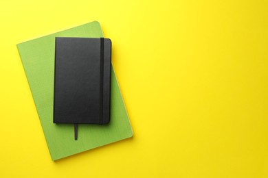 Different notebooks on yellow background, top view. Space for text