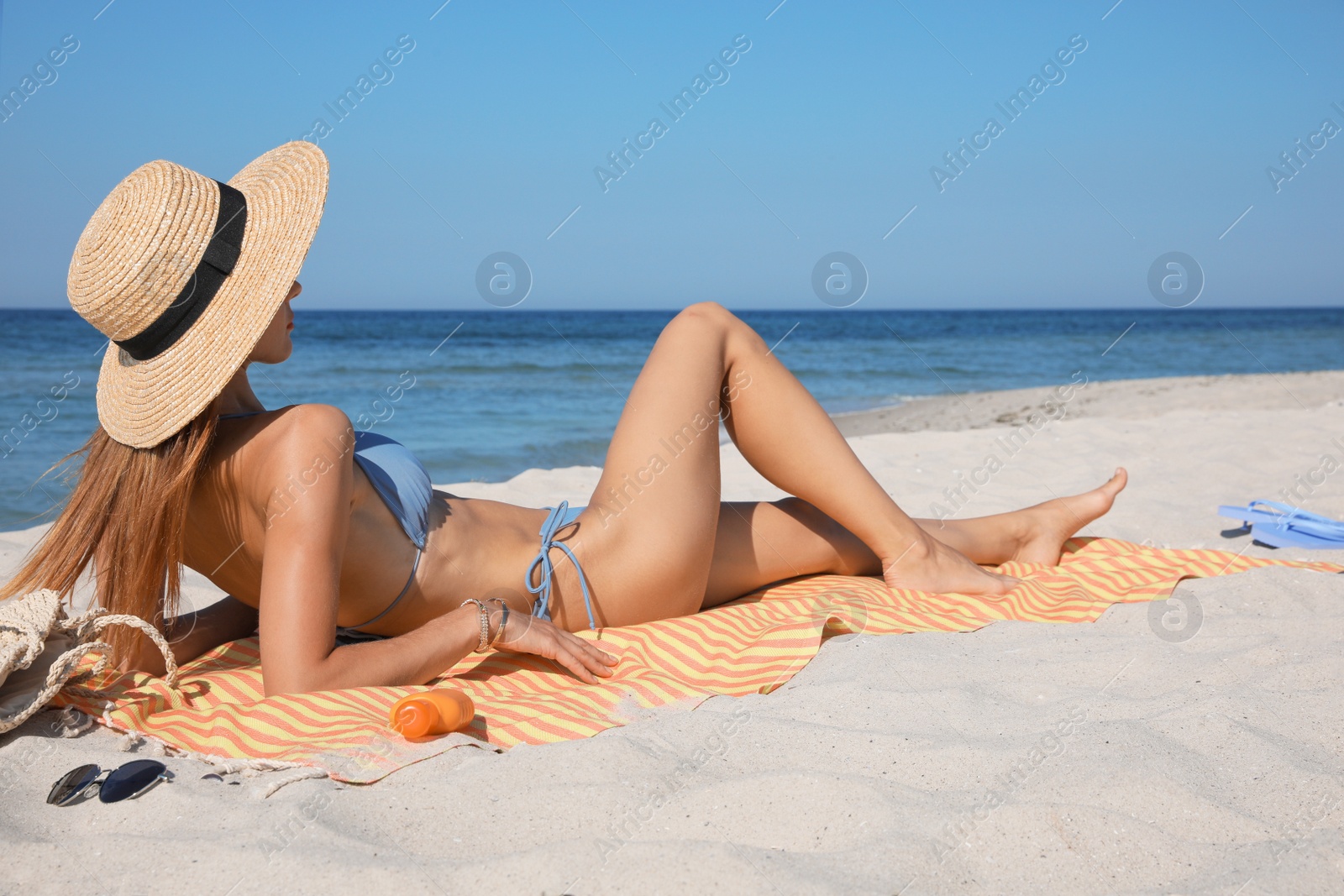 Photo of Woman with towel and other beach stuff on sand near sea