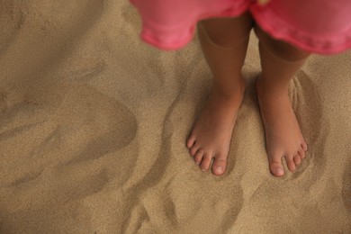 Little girl standing on sandy beach, closeup. Space for text