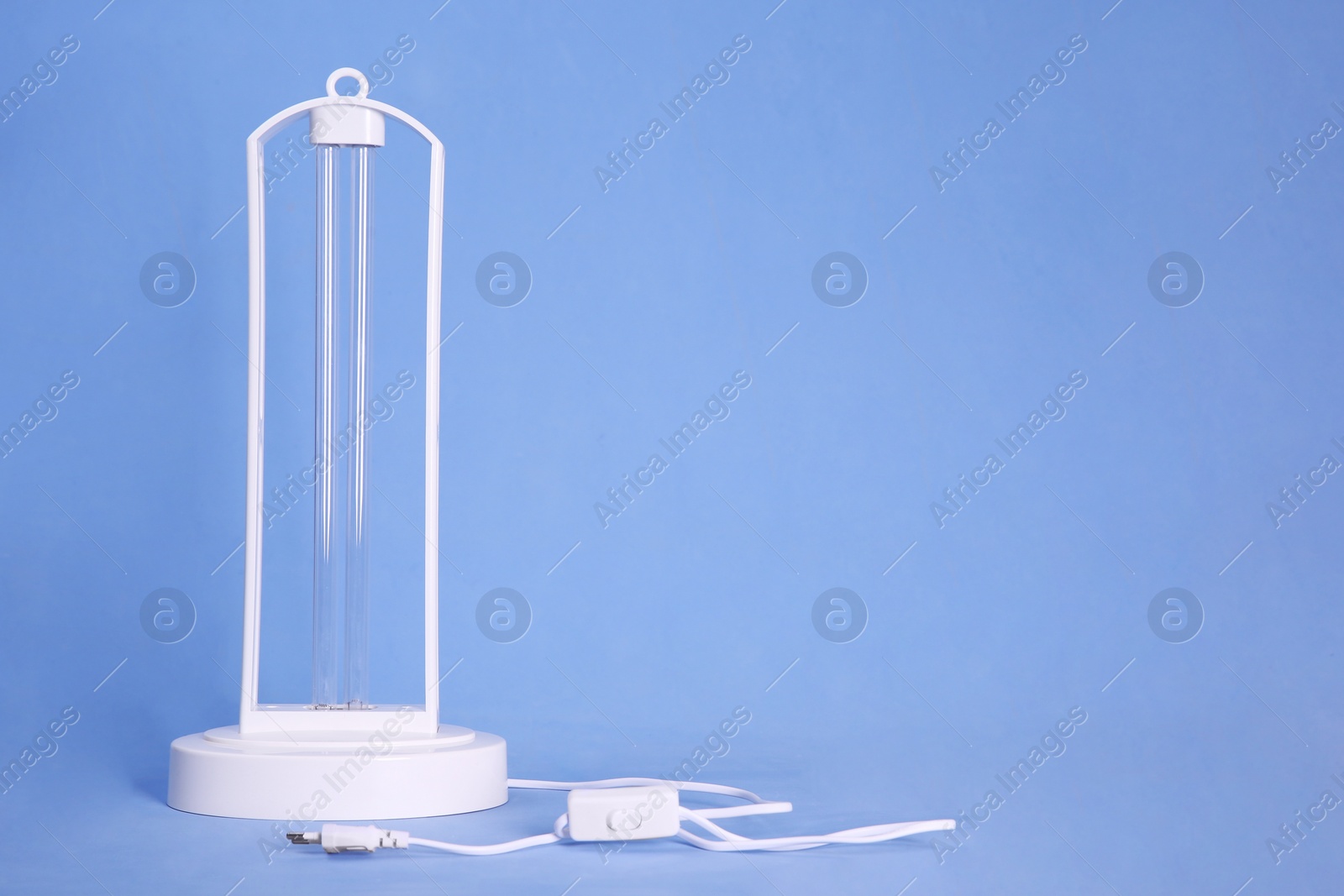 Photo of Ultraviolet lamp on blue background, space for text