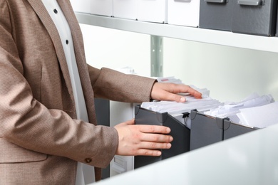 Woman taking documents from folder in archive, closeup