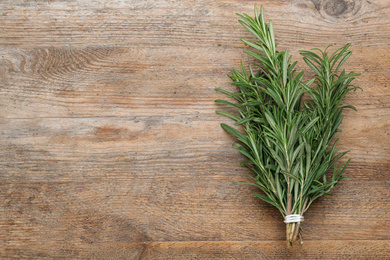 Bunch of fresh rosemary on wooden table, top view. Space or text