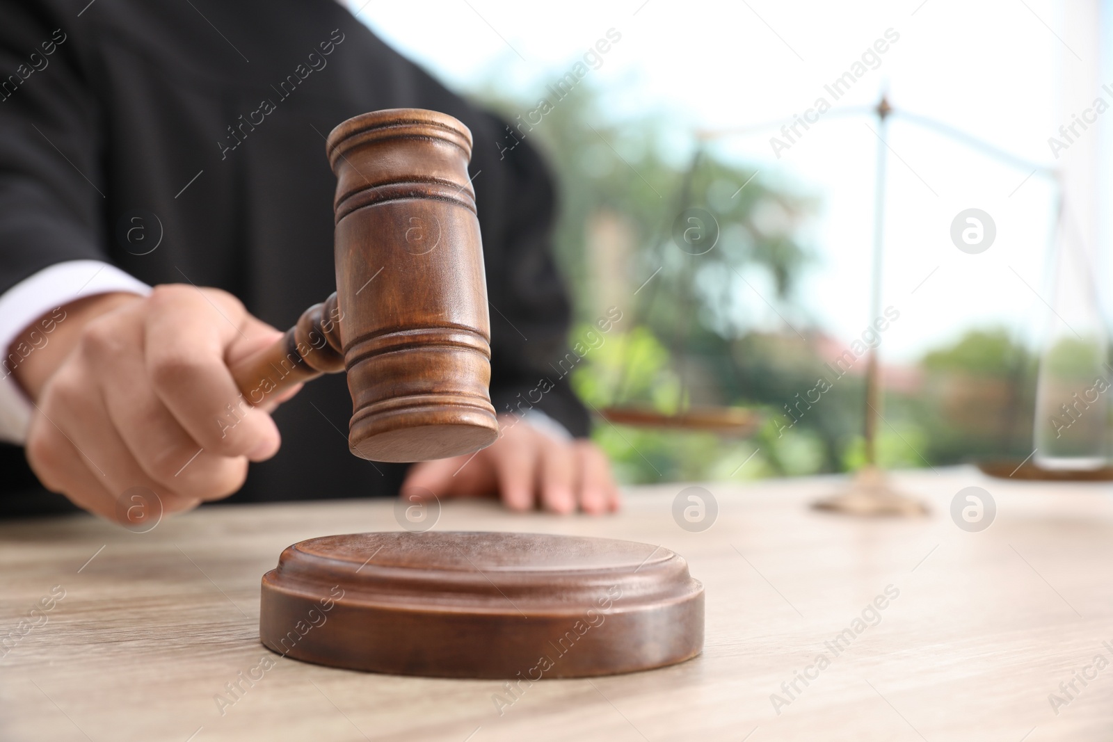 Photo of Judge with gavel at wooden table indoors, closeup. Criminal law