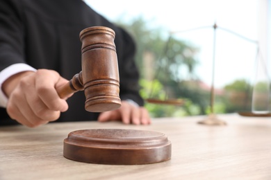 Judge with gavel at wooden table indoors, closeup. Criminal law