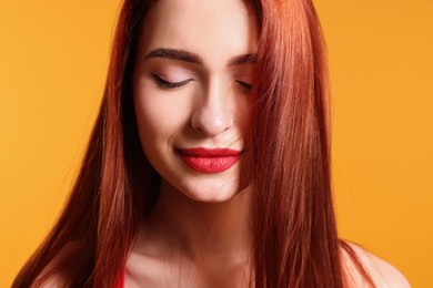 Photo of Beautiful woman with red dyed hair on orange background