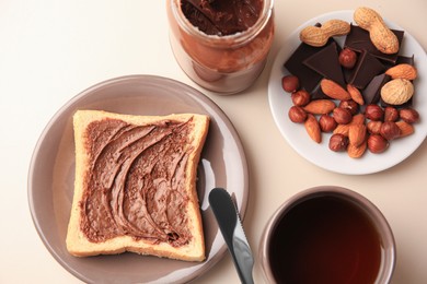 Tasty toast with chocolate paste and cup of tea served on light table, flat lay