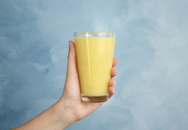 Woman holding glass with delicious smoothie on color background