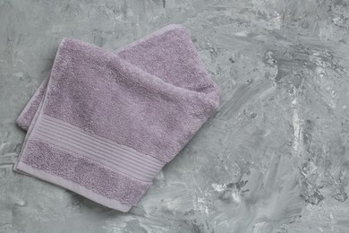 Photo of Violet terry towel on grey table, top view. Space for text