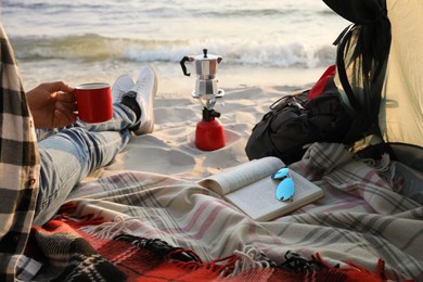 Man with cup of hot drink in camping tent, closeup