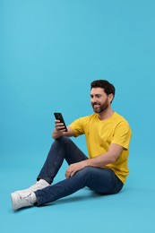 Photo of Smiling man with smartphone on light blue background