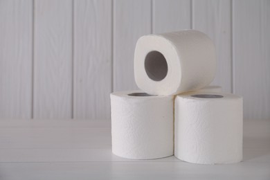 Photo of Many soft toilet paper rolls on white wooden table. Space for text