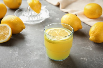 Photo of Glass with fresh lemon juice and fruits on table