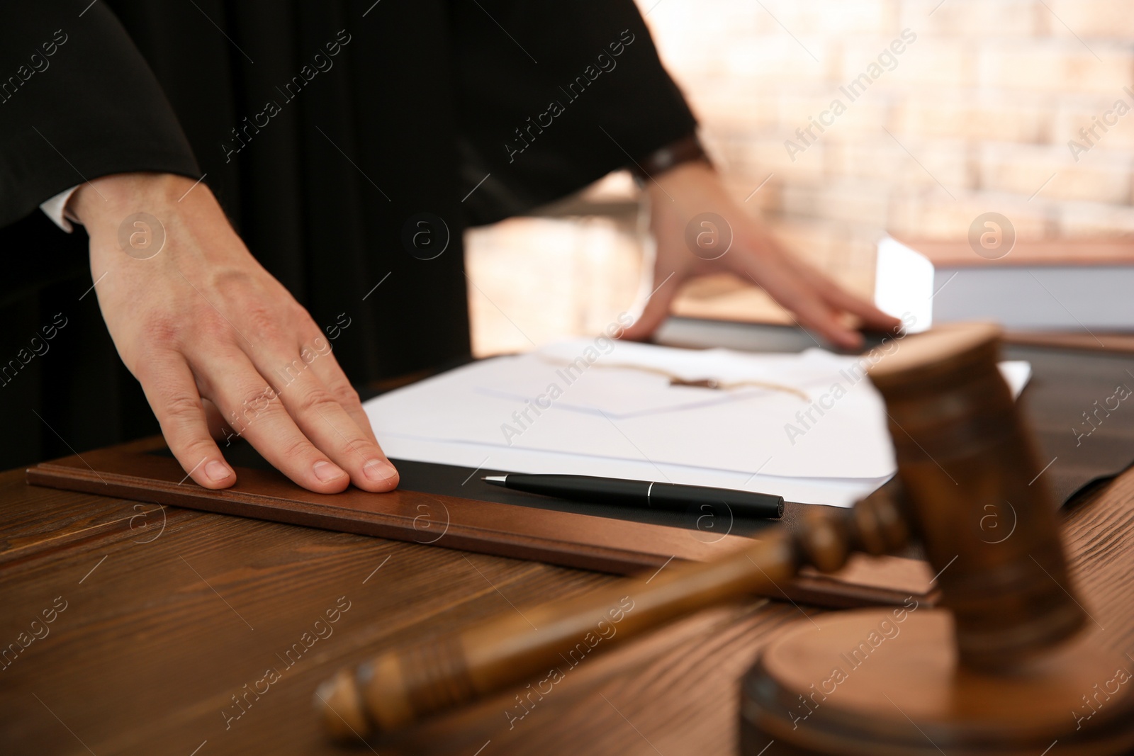 Photo of Judge with papers at table in office, closeup. Law and justice concept