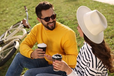 Photo of Beautiful young couple with takeaway coffee spending time together outdoors