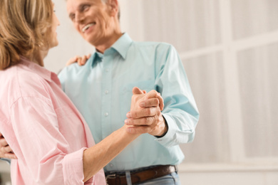 Photo of Happy senior couple dancing together at home, focus on hands