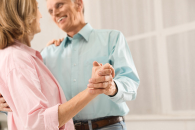 Happy senior couple dancing together at home, focus on hands