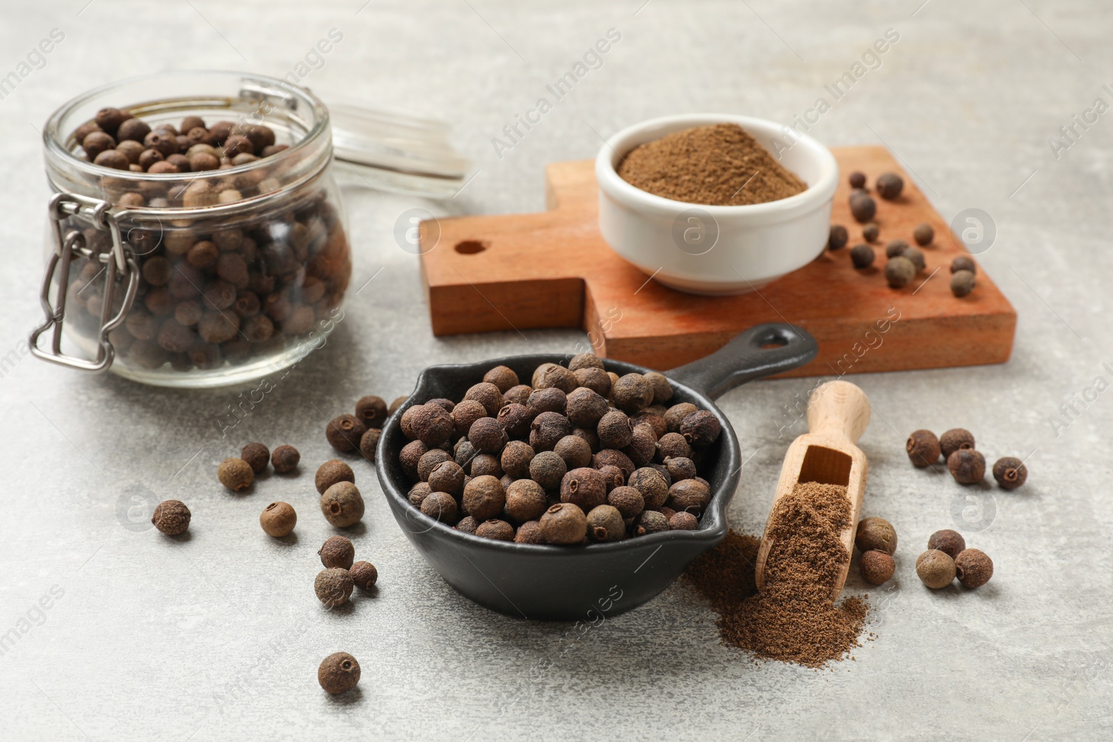 Photo of Aromatic allspice pepper grains and powder on grey table
