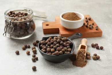 Photo of Aromatic allspice pepper grains and powder on grey table