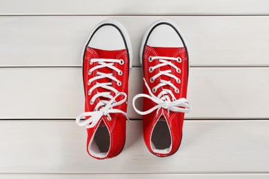 Photo of Pair of red sneakers on white wooden table, flat lay
