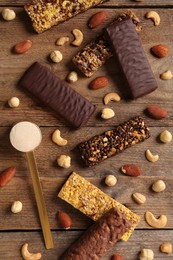 Different tasty bars, nuts and scoop of protein powder on wooden table, flat lay