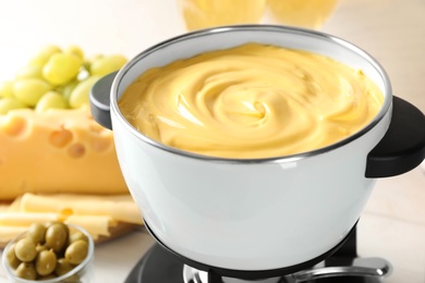 Photo of Pot with delicious cheese fondue on wooden table